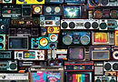 Retro TVs, boomboxes, and loudspeakers stacked on top of each other. The TV screens show a variety of BOXHOT imagery.